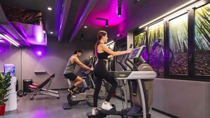 Un gimnasio con cintas de correr, una banca y un dispensador de agua.