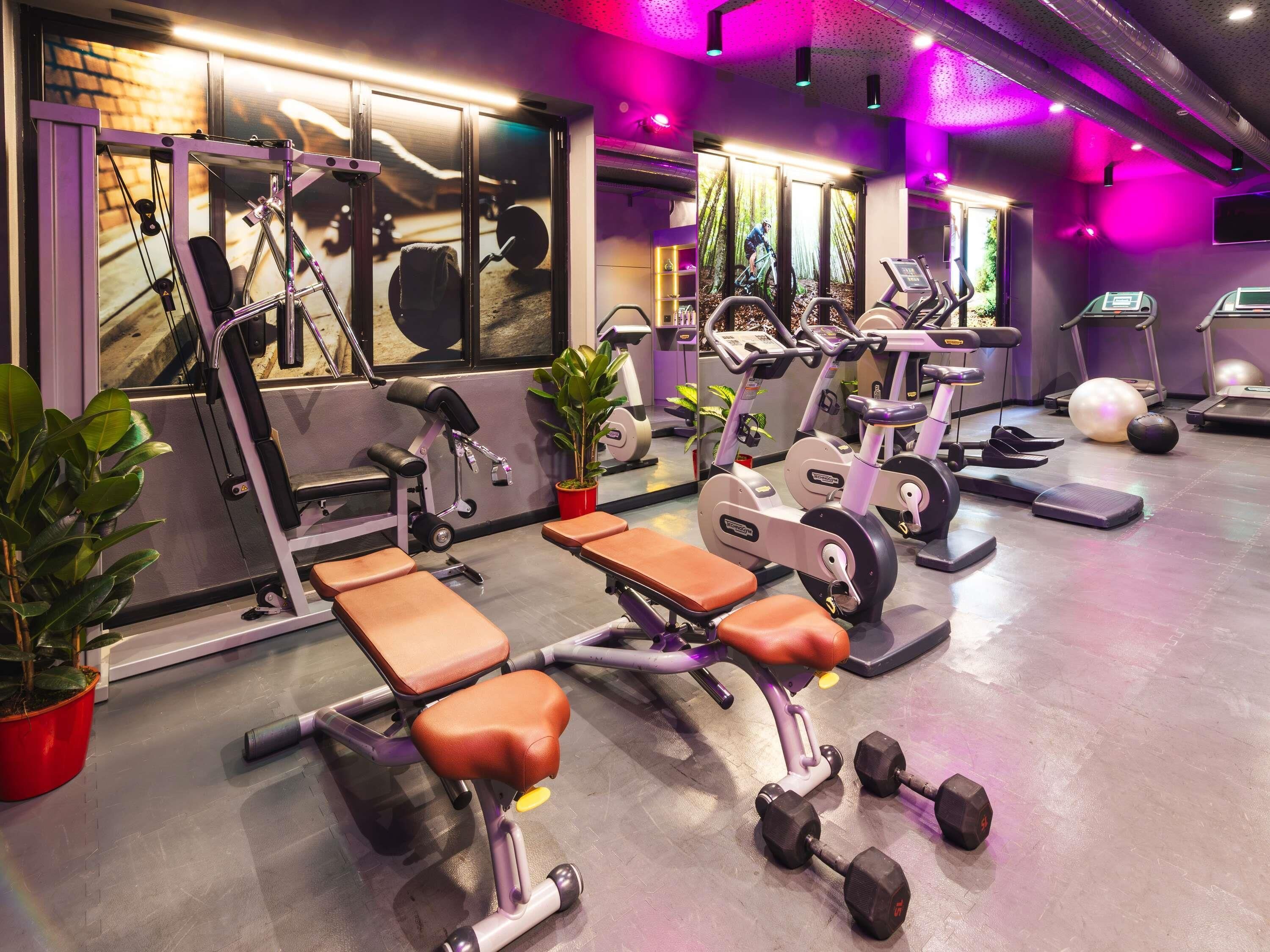 A gym with exercise equipment, benches, dumbbells, treadmills, and a mirror.