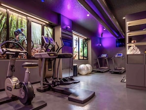 Un gimnasio con bicicletas estáticas, cintas de correr y pelotas de ejercicio.