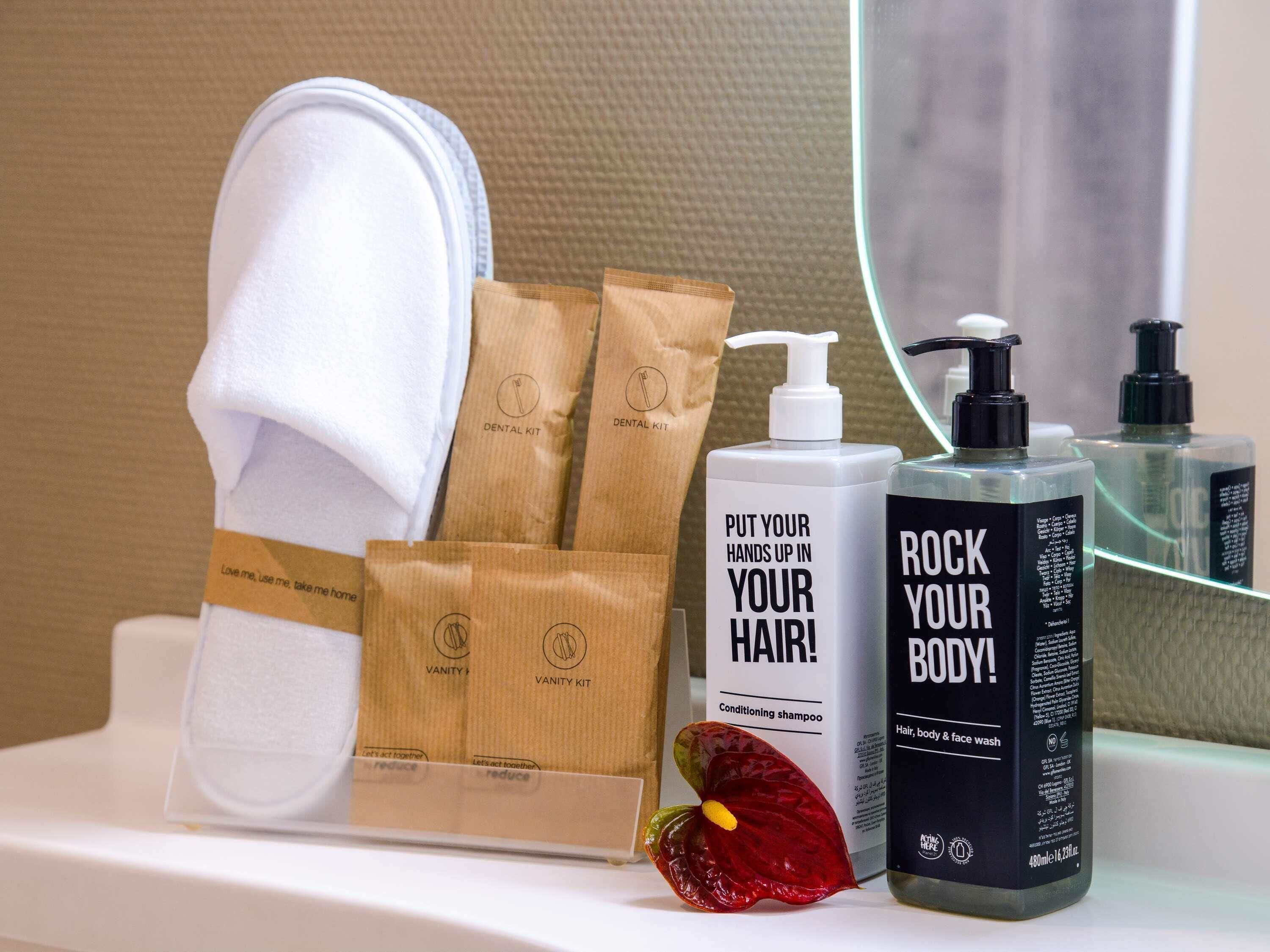 A bathroom vanity with a white towel, a mirror, and toiletries including a shampoo bottle and a conditioner bottle.