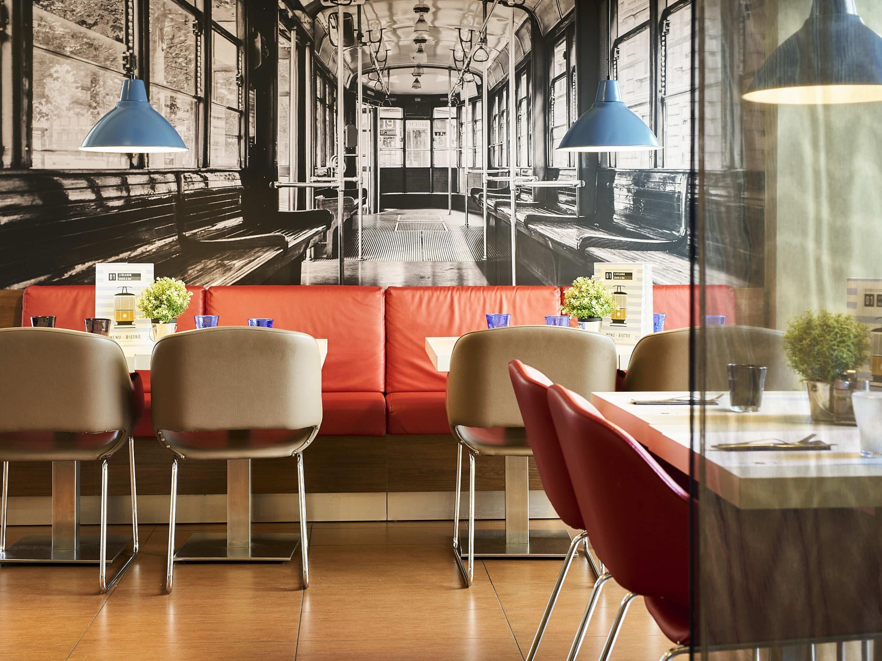 Interior de restaurante con cabinas, mesas y lámparas colgantes azules.