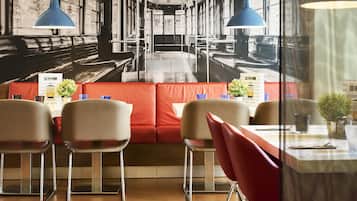 Interior de restaurante con cabinas, mesas y lámparas colgantes azules.
