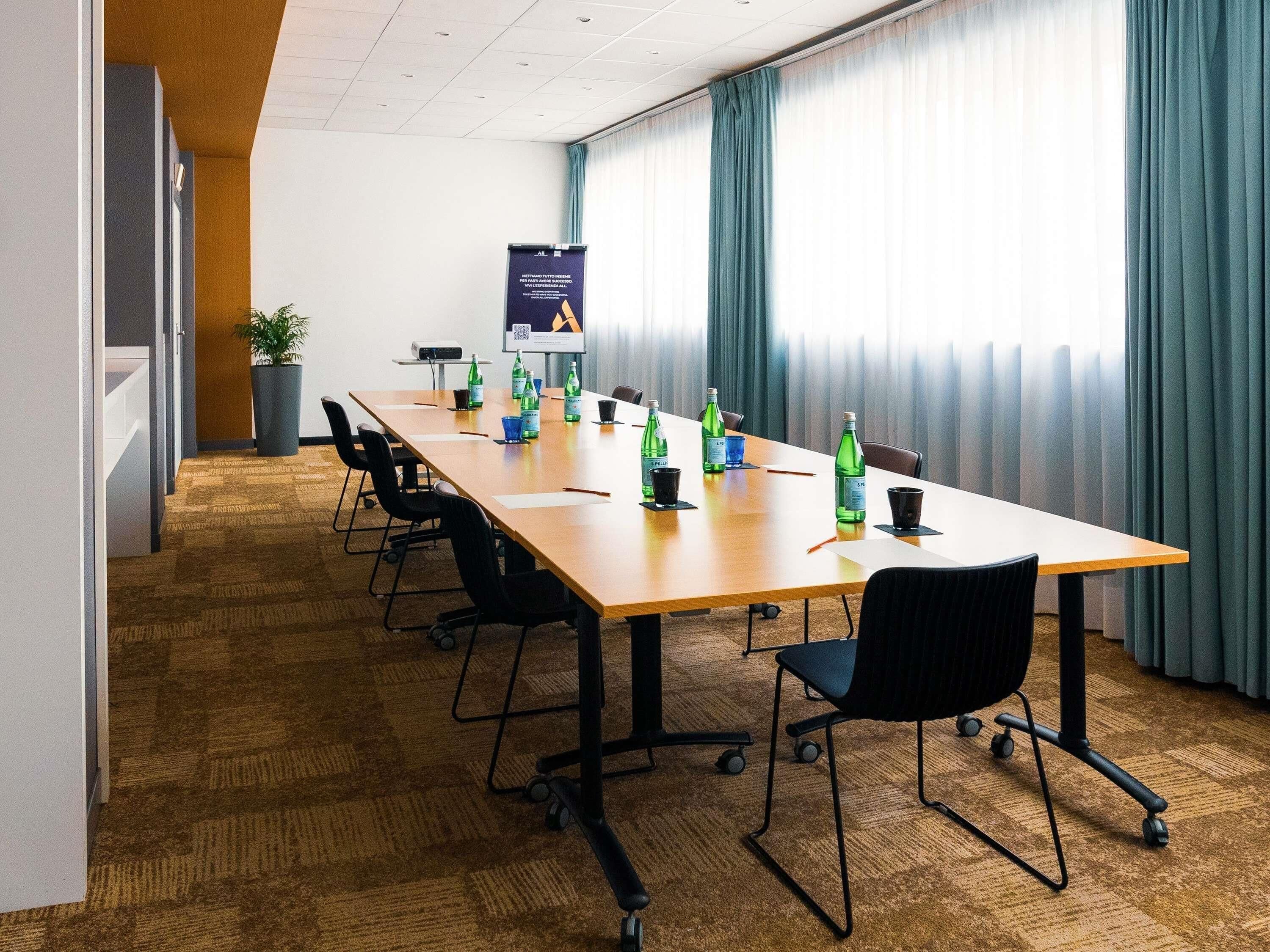 Een vergaderzaal met een lange tafel, stoelen en een projectorscherm.