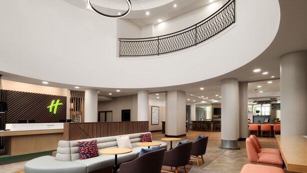 Un hall d’hôtel moderne comprenant un comptoir d’accueil, un espace salon et un escalier.