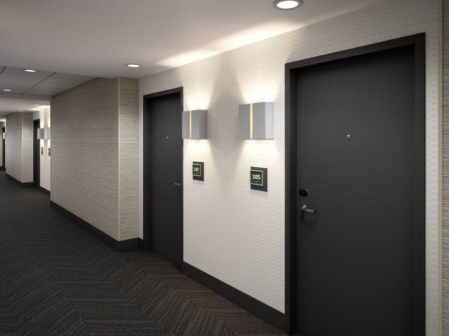 Un corridoio con porte scure, numeri civici e illuminazione a incasso.
