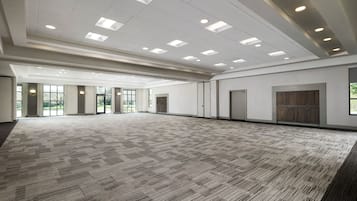 A spacious conference room with a patterned carpet, recessed ceiling lights, and large windows.