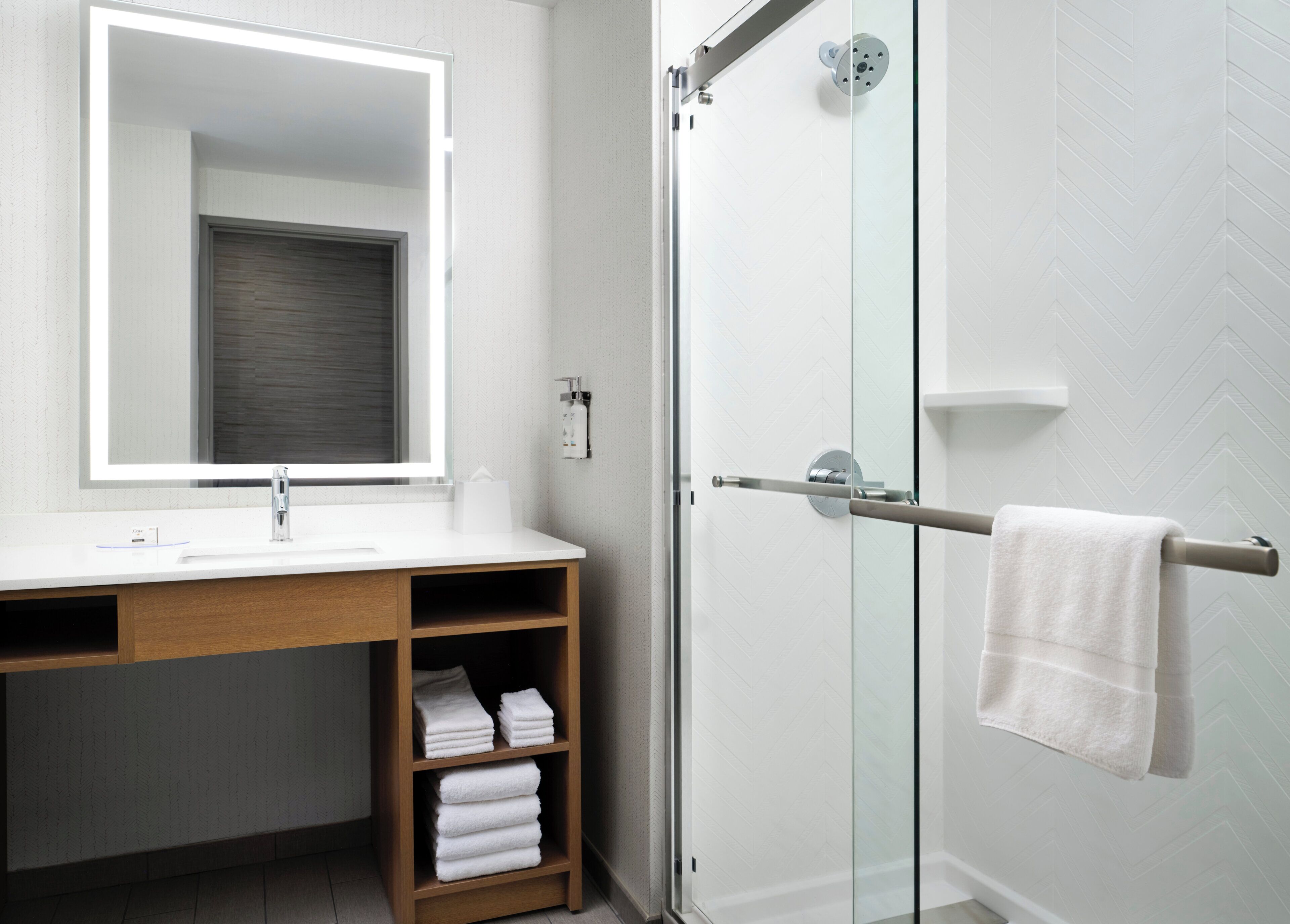 A modern bathroom with a glass shower door, a white sink, a mirror, and a towel rack.