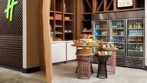 Un espace de vente moderne, doté d'étagères en bois, d'un présentoir réfrigéré et de paniers en osier disposés sur des tables.