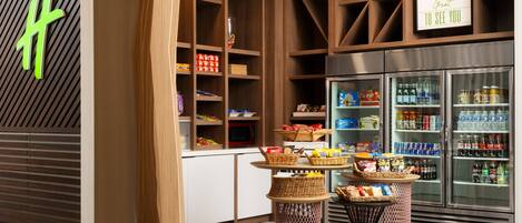 A modern retail space with wooden shelving, a refrigerated display, and wicker baskets on tables.