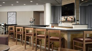 Un espace bar avec des tabourets de bar en bois, un long comptoir et un téléviseur fixé au mur.