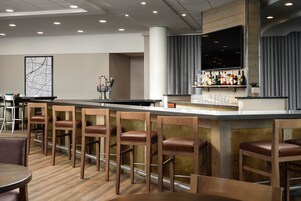 A bar area with wooden bar stools, a long counter, and a mounted TV.