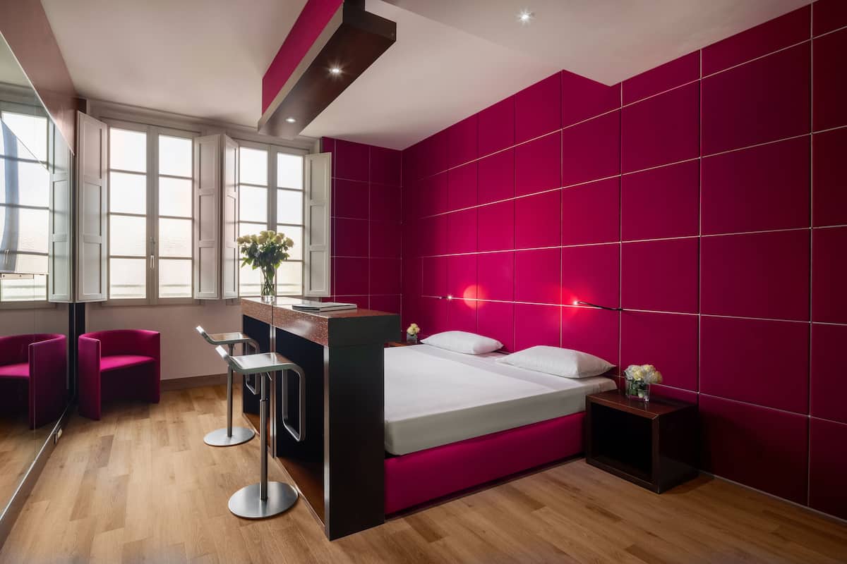 A modern bedroom with a large bed, a desk, and two chairs.