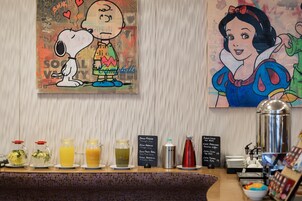 Una colazione a buffet con diverse bevande e un cartellone con il menu.