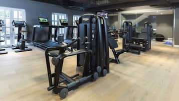 Un gimnasio con cintas de correr, máquinas de pesas y un espejo grande.