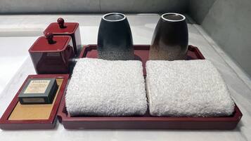 A set of toiletries on a tray, including a soap bar, two bottles, and two towels.