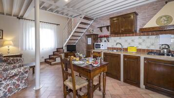 Eine Küche mit Holzausstattung, einem Esstisch mit Stühlen, einer Treppe und einem Wohnbereich mit Sofa und Lampe.