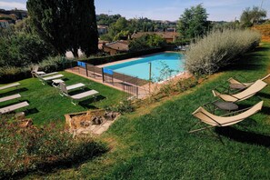 A swimming pool with lounge chairs, a grassy area, and a view of the surrounding landscape.
