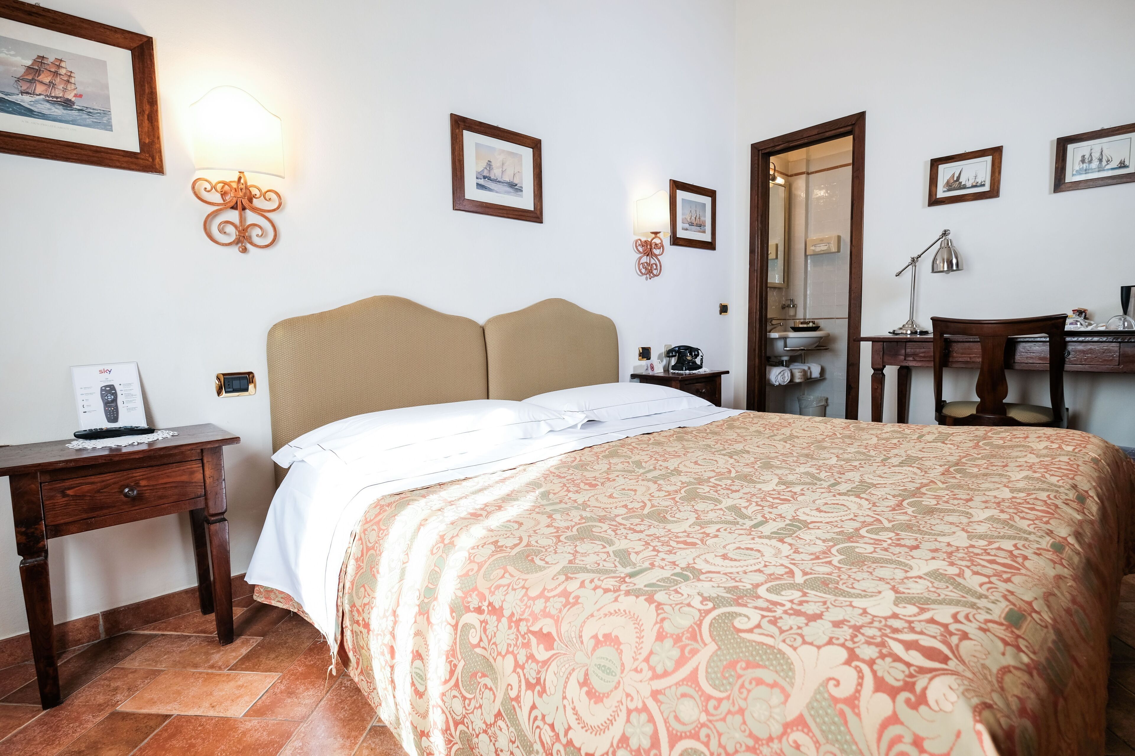 Ein Hotelzimmer mit Bett, Schreibtisch, Stuhl, Spiegel und einer Wandlampe.