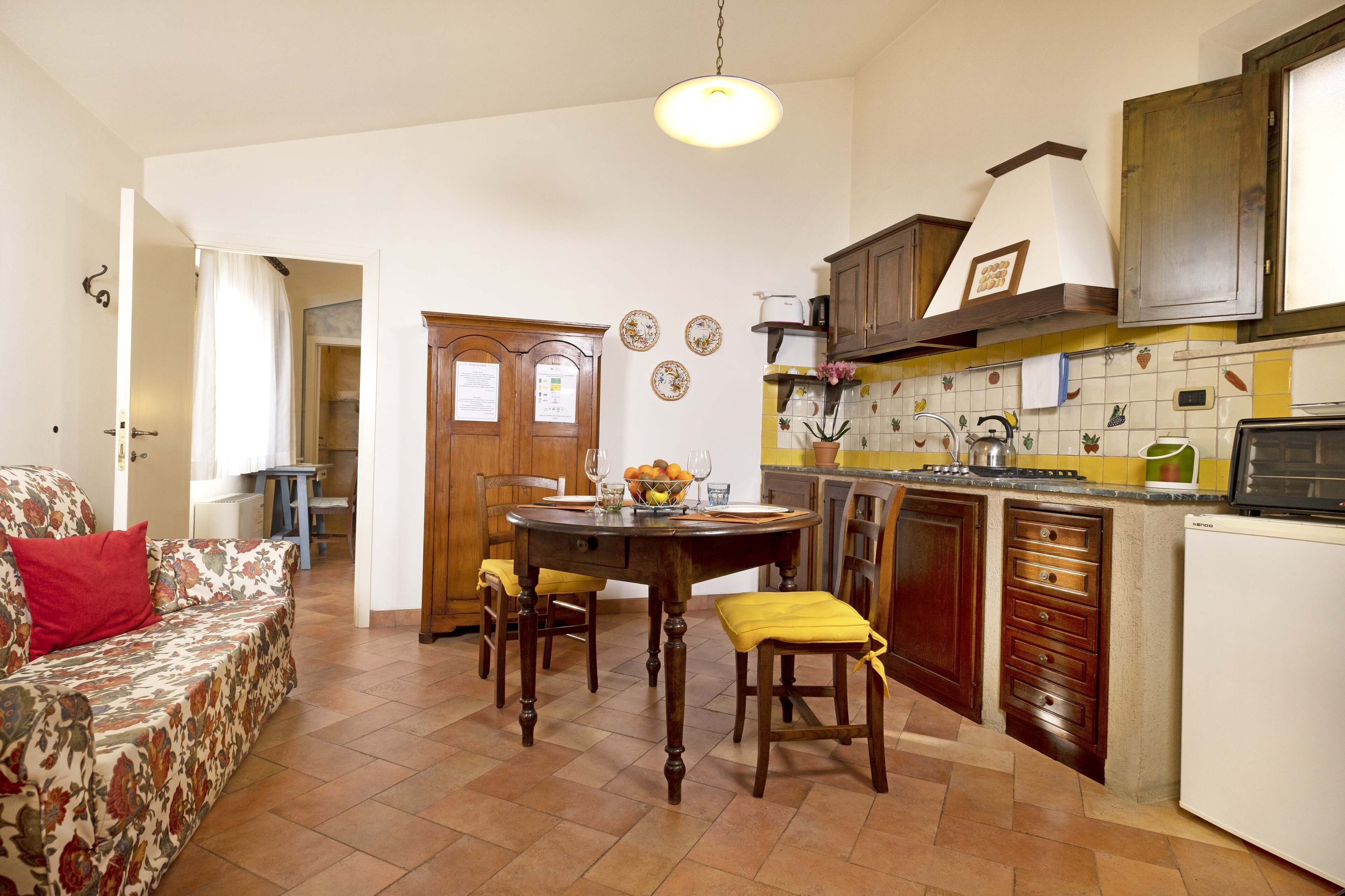 A compact kitchen with a dining table, chairs, and a refrigerator.