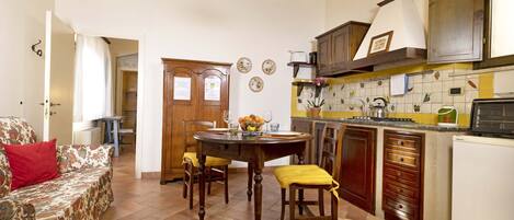 A compact kitchen with a dining table, chairs, and a refrigerator.