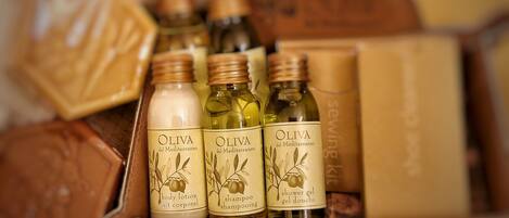 Une boîte contenant trois flacons de produits à base d’huile d’olive, notamment une lotion pour le corps, un shampooing et un gel douche.