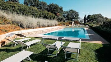 Una piscina al aire libre de temporada, sillones reclinables de piscina