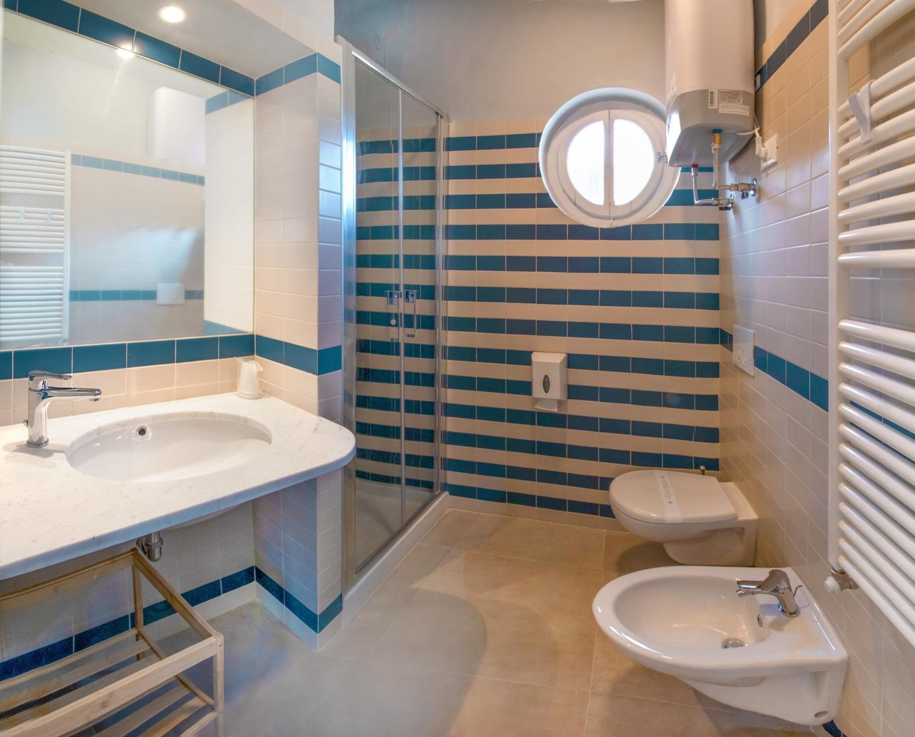 Un baño con dos lavamanos, ducha e inodoro con lavado trasero.