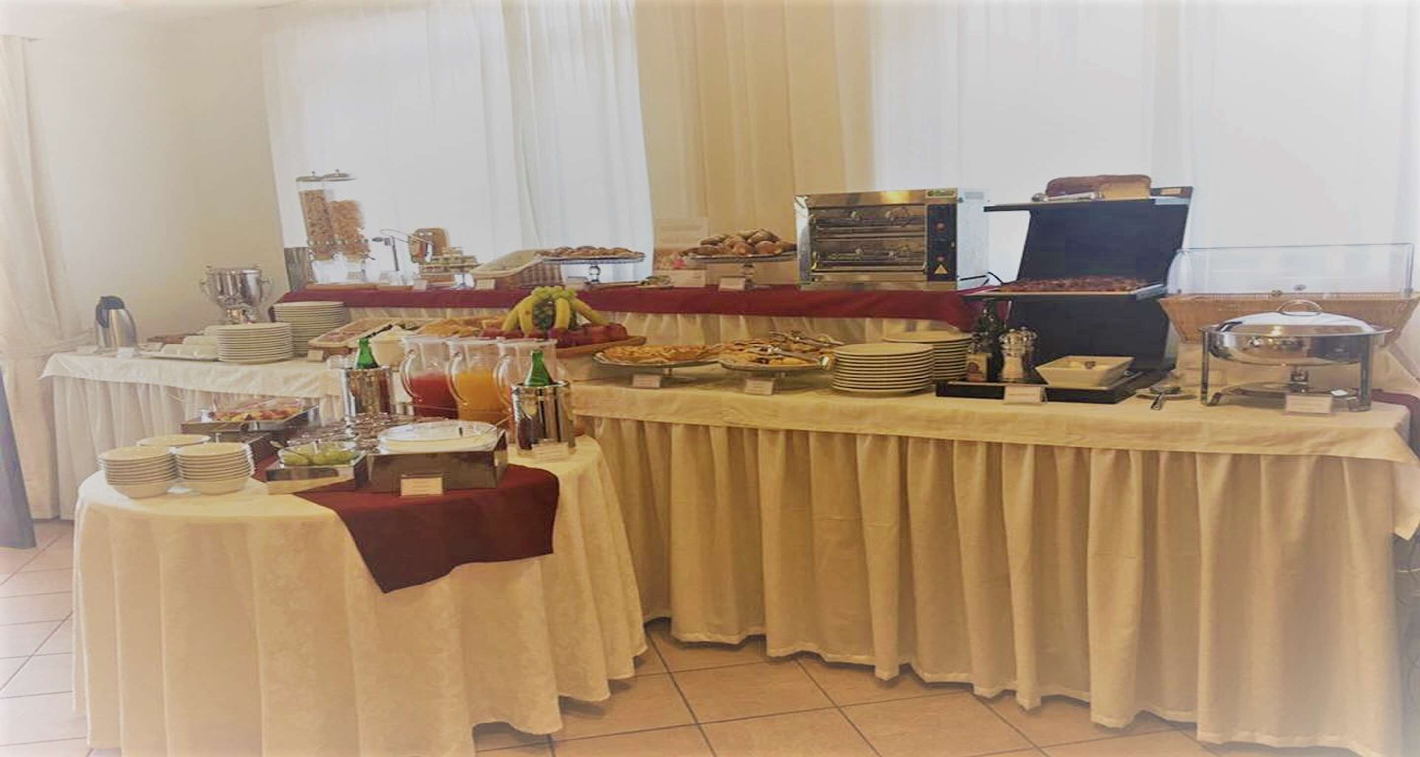 A buffet setup with various food items, a coffee station, and a fruit display.