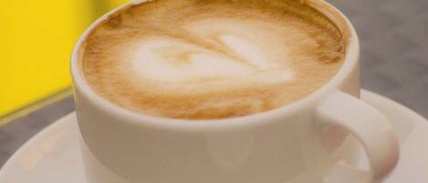A cup of coffee with a heart-shaped latte art on a white saucer.