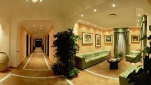 Un vestíbulo de hotel espacioso con un largo pasillo, zonas de estar y un mostrador de recepción.