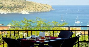 Ein Tisch mit Frühstücksangeboten und Blick auf das Meer mit Booten.