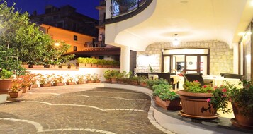 Un patio con plantas en macetas y asientos exteriores, rodeado de edificios.