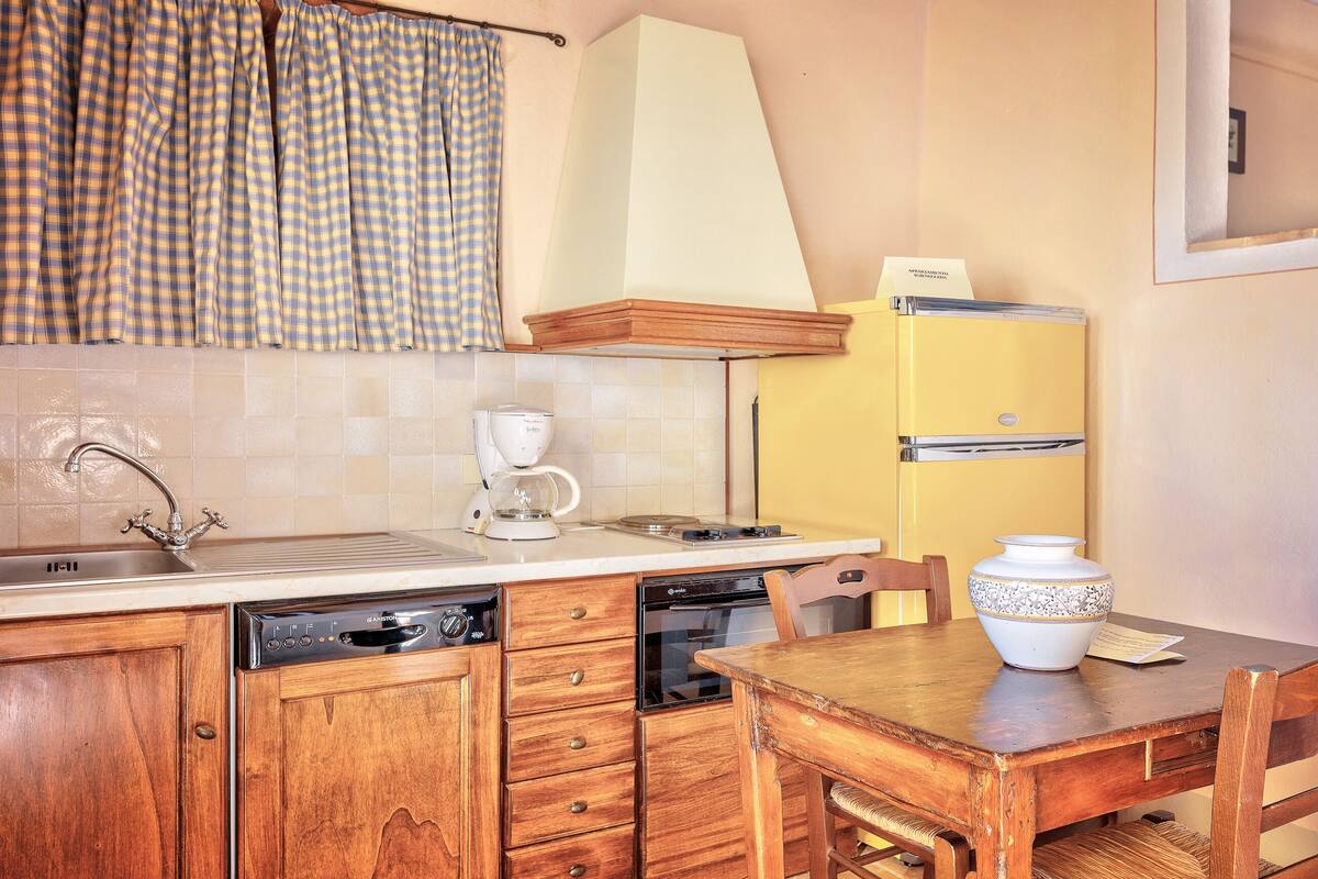 A kitchen with wooden cabinets, a dishwasher, a coffee maker, and a yellow refrigerator.
