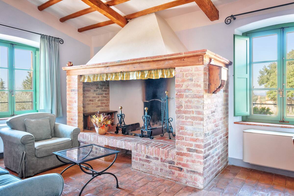 A cozy living room with a brick fireplace, a comfortable sofa, and a table.