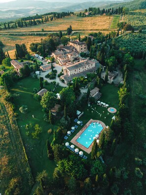 Vista aérea de una extensa propiedad con varias construcciones, piscina y jardines cuidados.