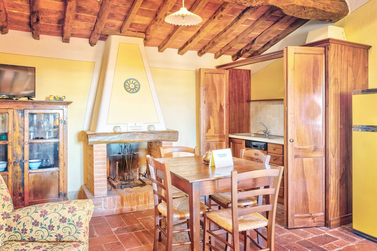 A rustic kitchen with wooden cabinets, a brick fireplace, and a dining table with chairs.