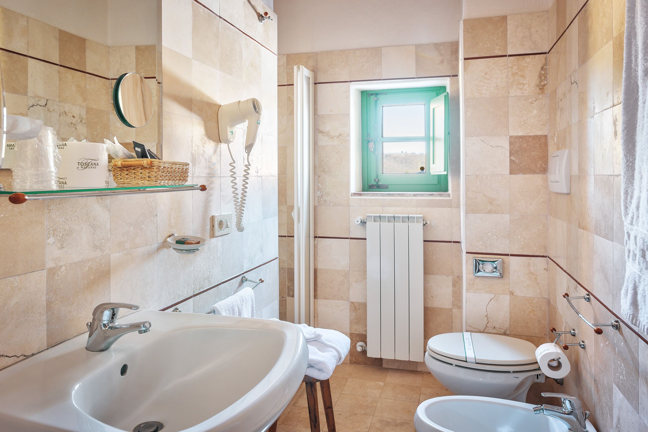 A bathroom with a large sink, toilet, and a small window.