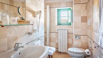 Une salle de bain avec un grand lavabo, des toilettes et une petite fenêtre.