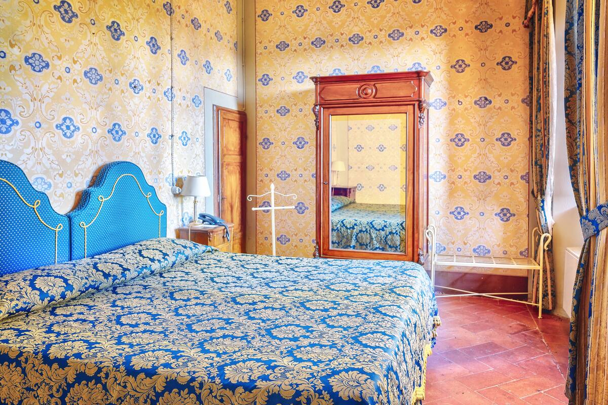 A room with a bed, a mirror, and a wardrobe.