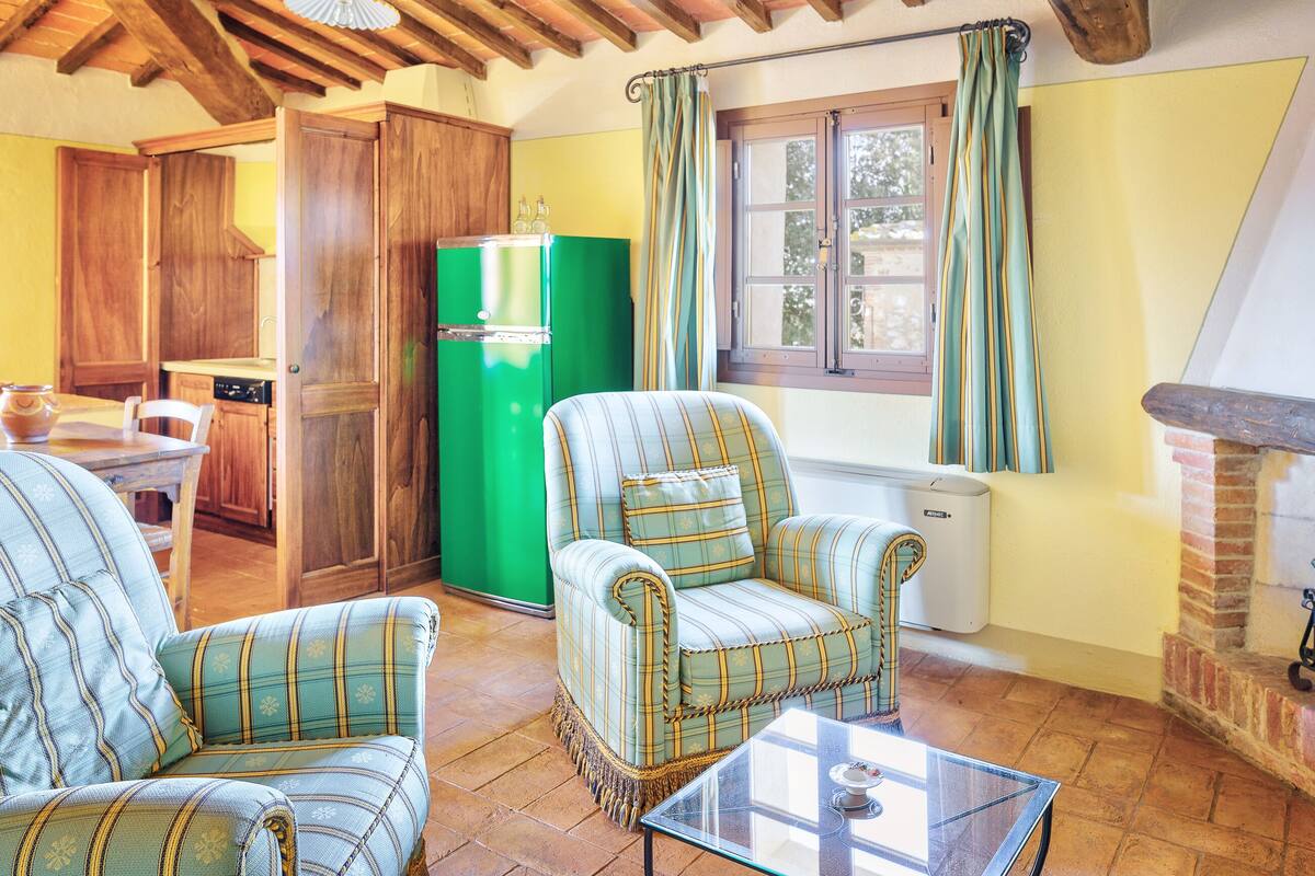 A cozy living room with two striped armchairs, a green refrigerator, and a glass coffee table.