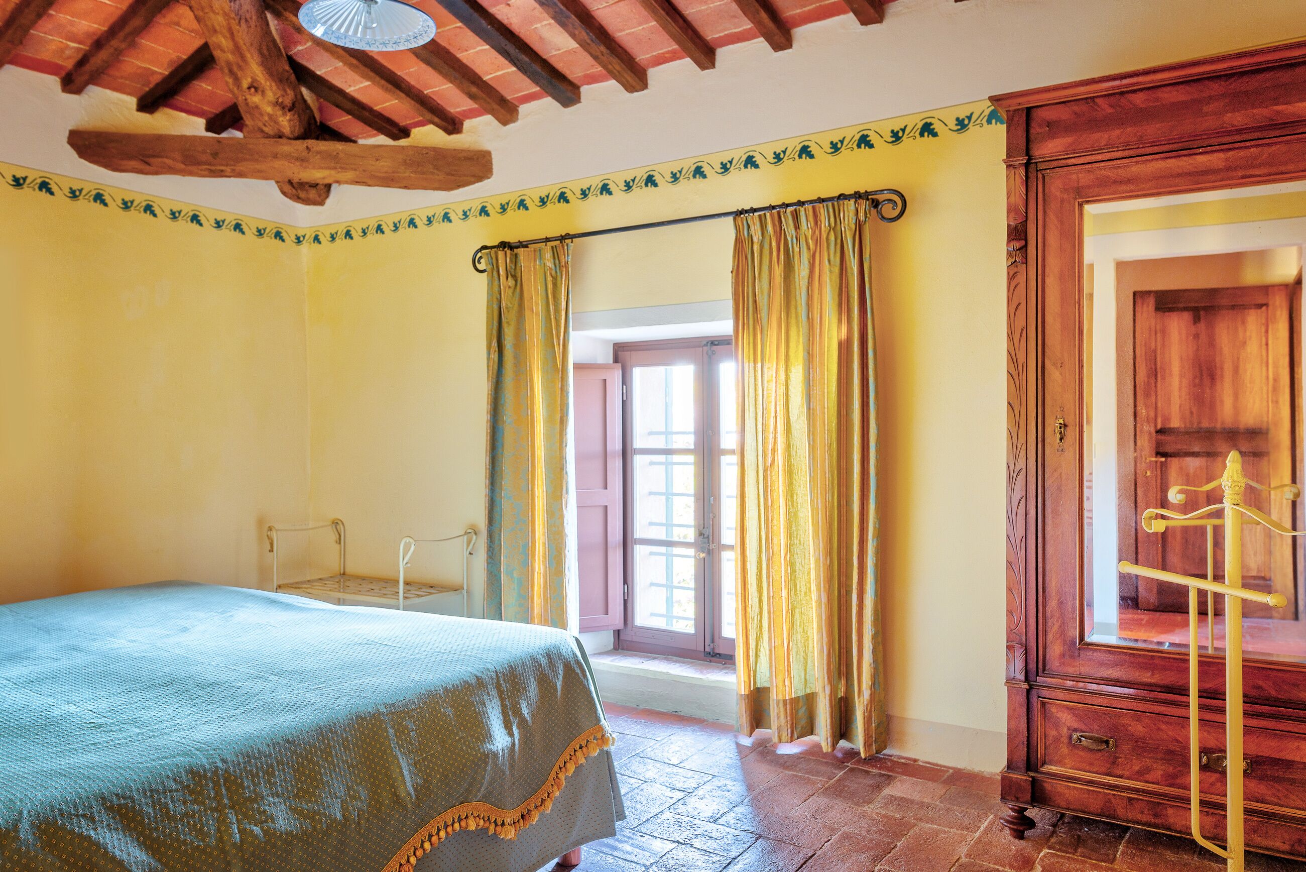 Un dormitorio con cama, armario de madera y ventana con cortinas.