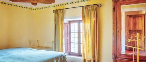 Un dormitorio con cama, armario de madera y ventana con cortinas.