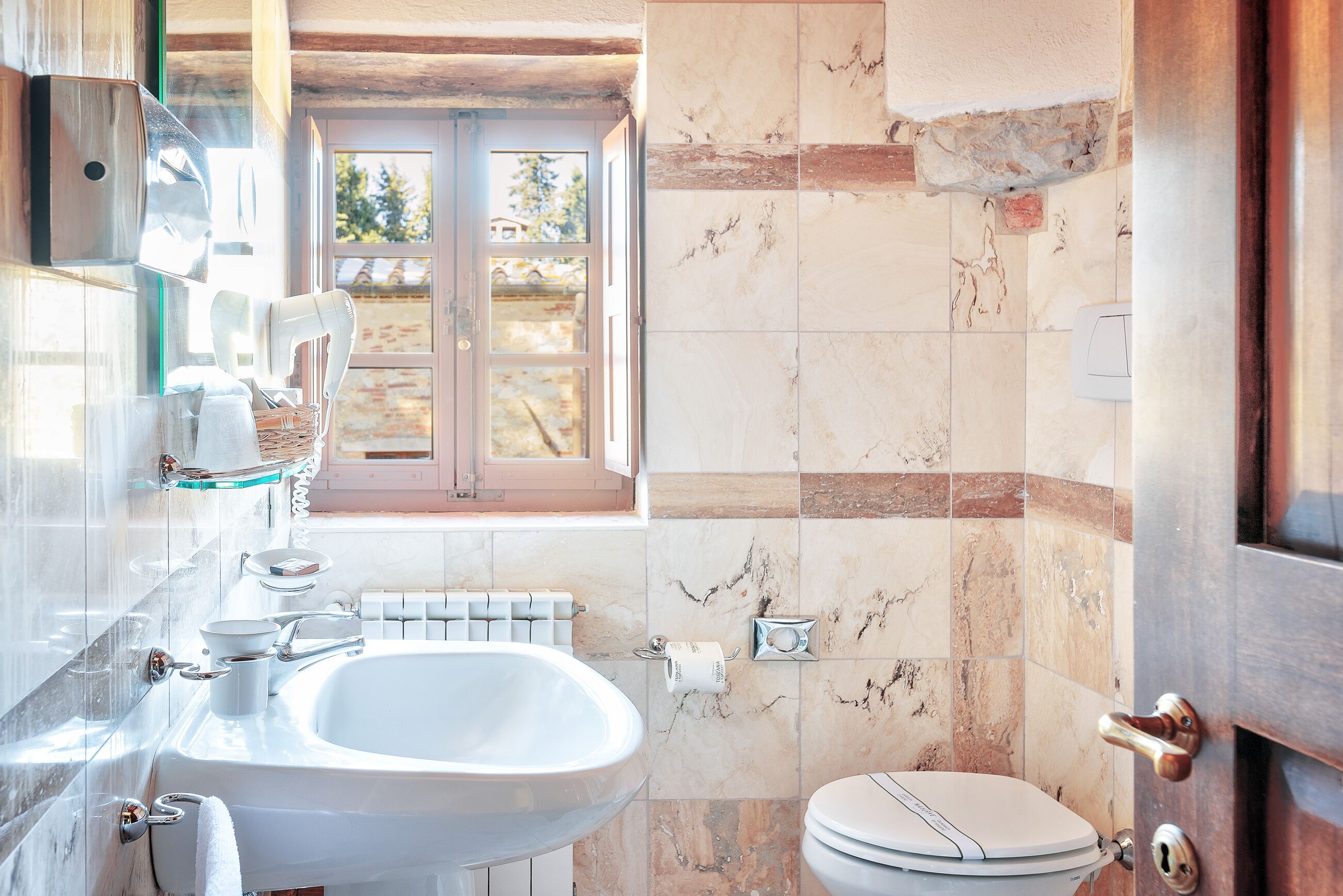 Une salle de bain avec un lavabo, des toilettes et une fenêtre.