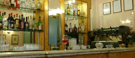 A bar area with shelves of liquor bottles, glasses, and a coffee machine.