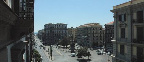 A city street with buildings on both sides, a clear sky, and a few cars on the road.