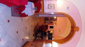A hotel lobby with a marble floor, a red sofa, a wooden reception desk, and a large mirror reflecting the space.