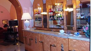 A bar area with a marble countertop, a white lamp, and shelves with liquor bottles.