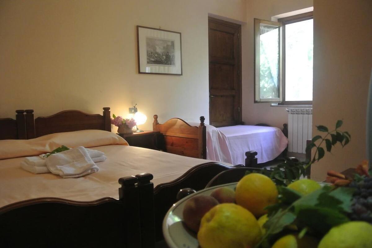 A bedroom with a bed, bedside table, lamp, and a window.