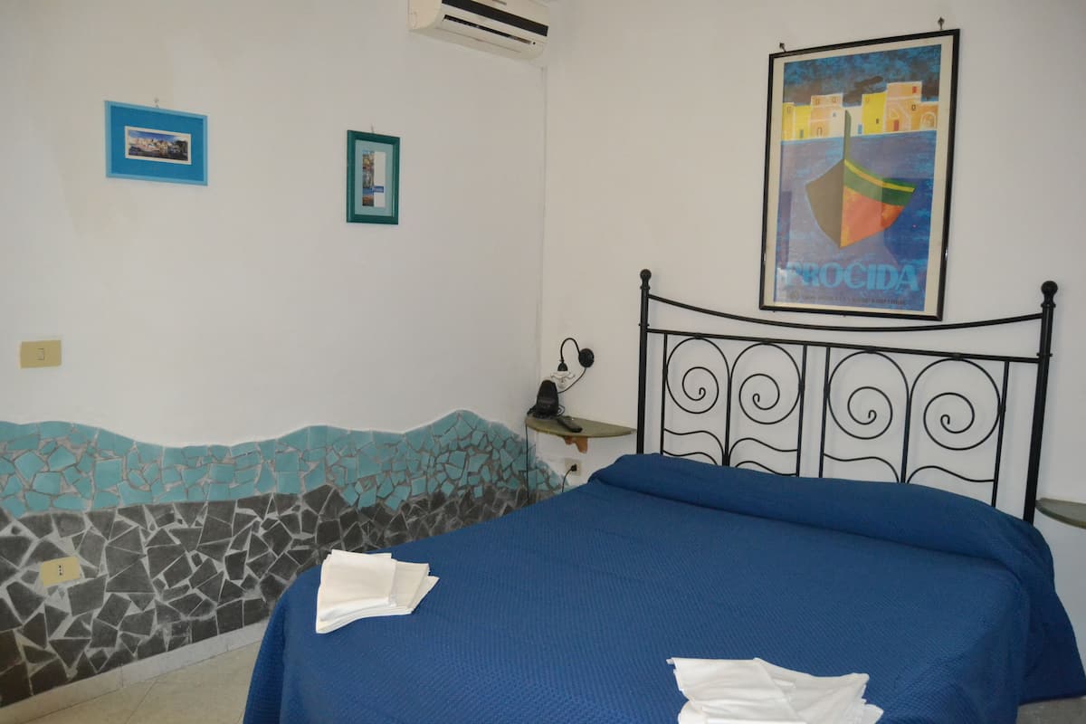 Une chambre à coucher avec un lit, une table de chevet et un mur orné d’une affiche.