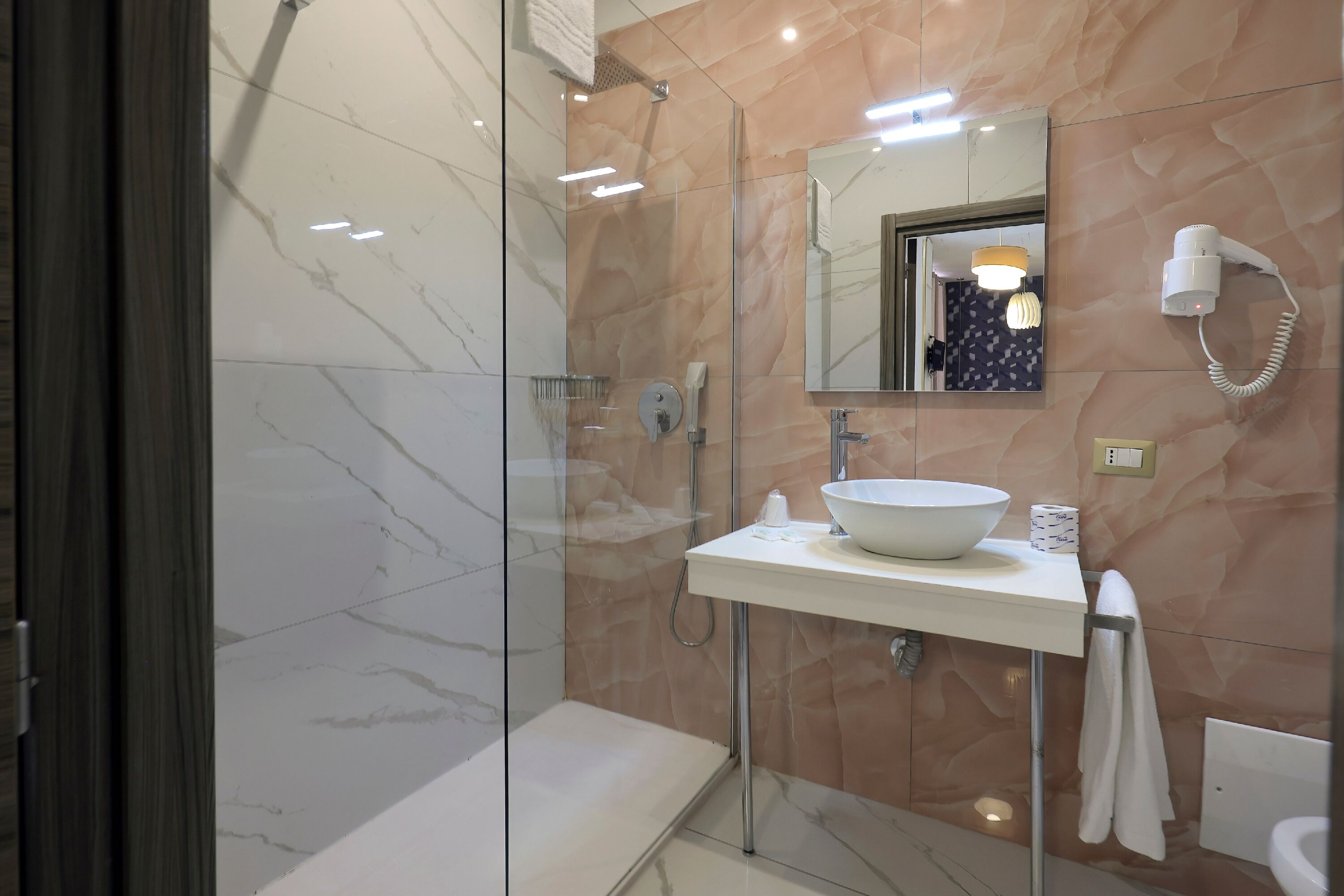 A modern bathroom with a glass-enclosed shower, a white sink, and a mirror above it.